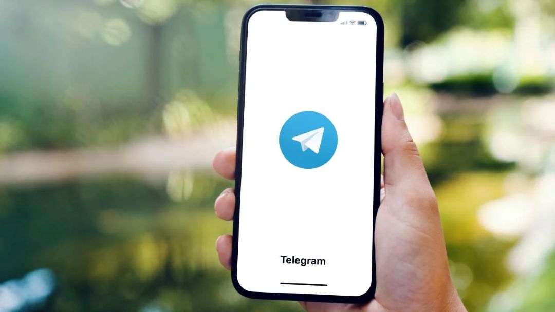 Hand holding smartphone with Telegram app