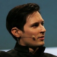 Pavel Durov (Telegram founder) wearing a black jacket is seated, appearing relaxed and contemplative in his surroundings.