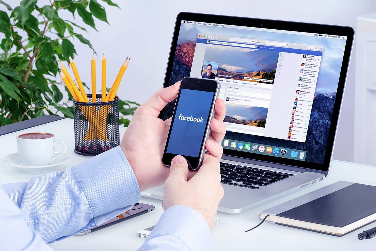 A smartphone displaying a Facebook page with likes and hearts flying up, symbolizing growing trust and engagement.